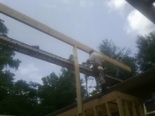 Carpenter setting a ridge beam over a new addition frame — Ice Dam Removal by Roofing Brothers in Mountain Ranch