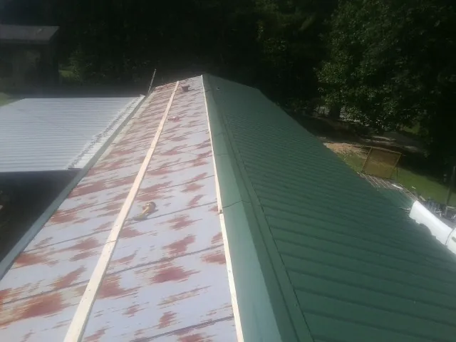 Old rusted panels beside newly installed green metal roofing — Wind Damage Roof Repair by Roofing Brothers in Mountain Ranch