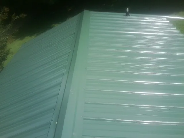 New green metal panels meeting at the ridge of a roof — Flat Roof Repair work by our crew in Mountain Ranch