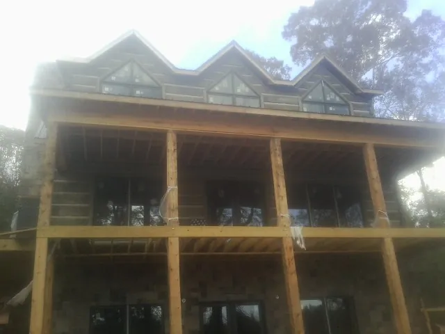 Dormers and porch framing on a large log home under construction — Roof Coating work by our crew in Mountain Ranch