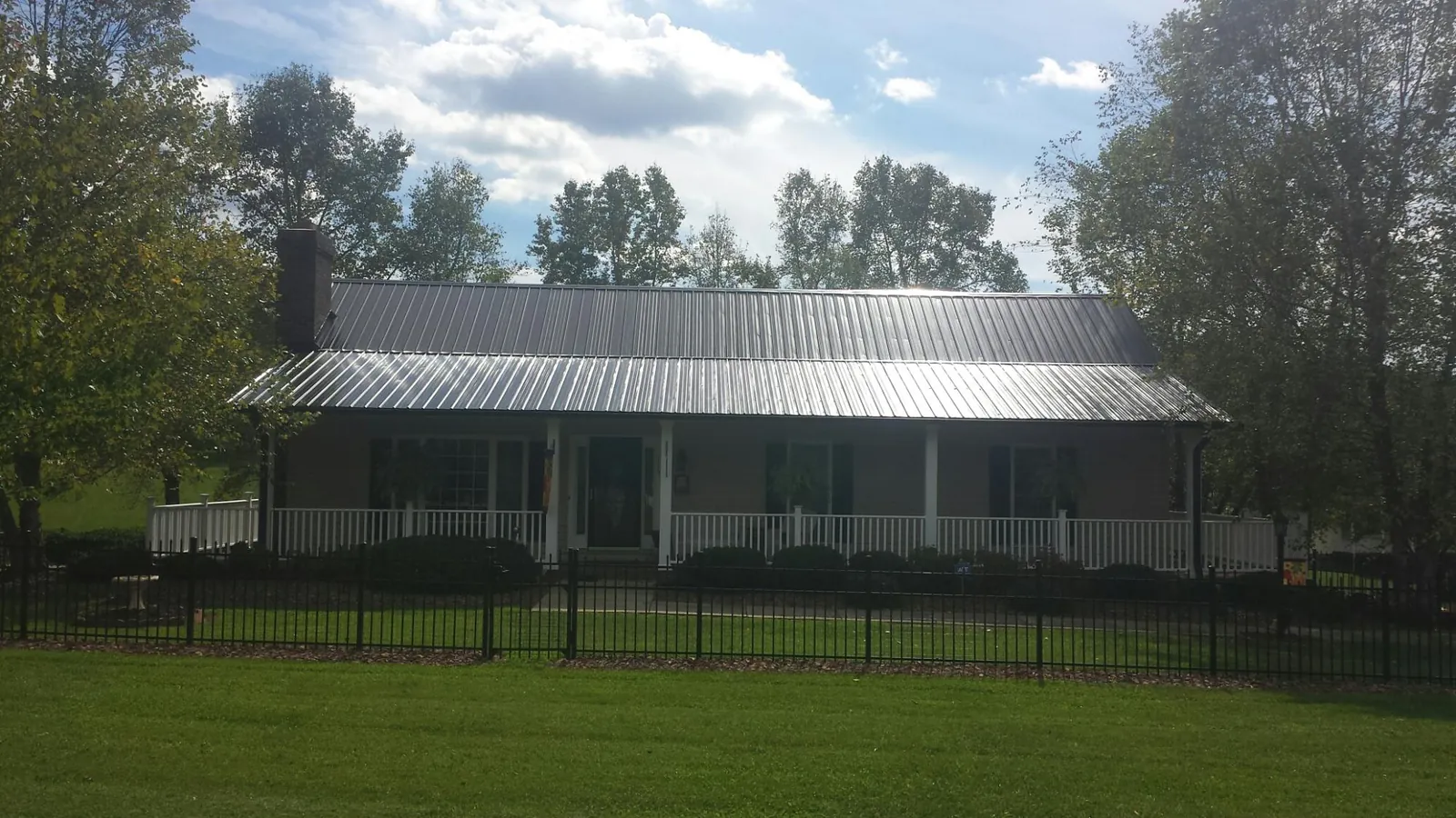 Gray metal roof on a brick ranch with a full width front porch — Gutter Guard Installation work by our crew in Mountain Ranch