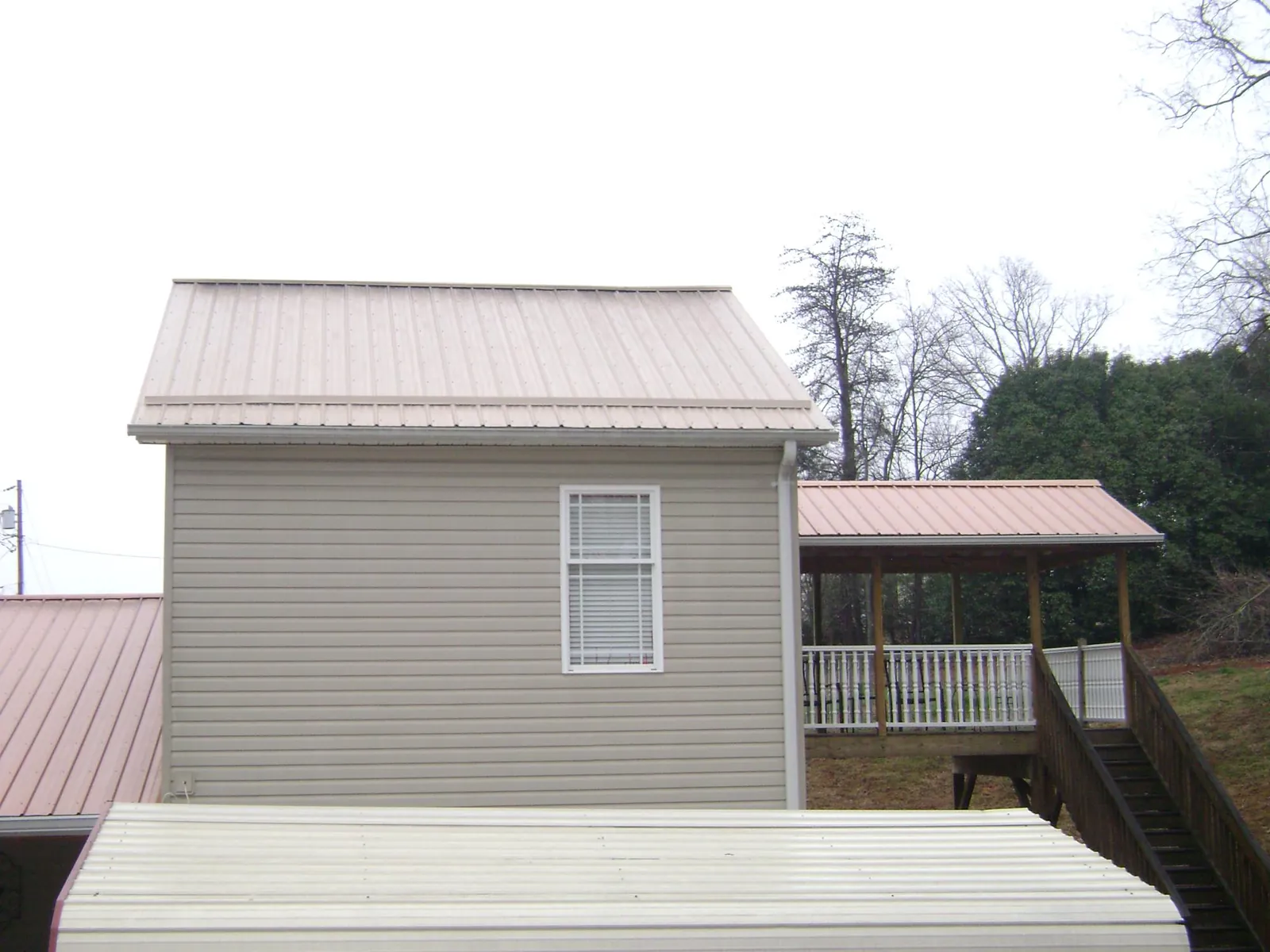 Tan metal roofs on a two story addition and attached porch, from a Roof Replacement job in Mountain Ranch