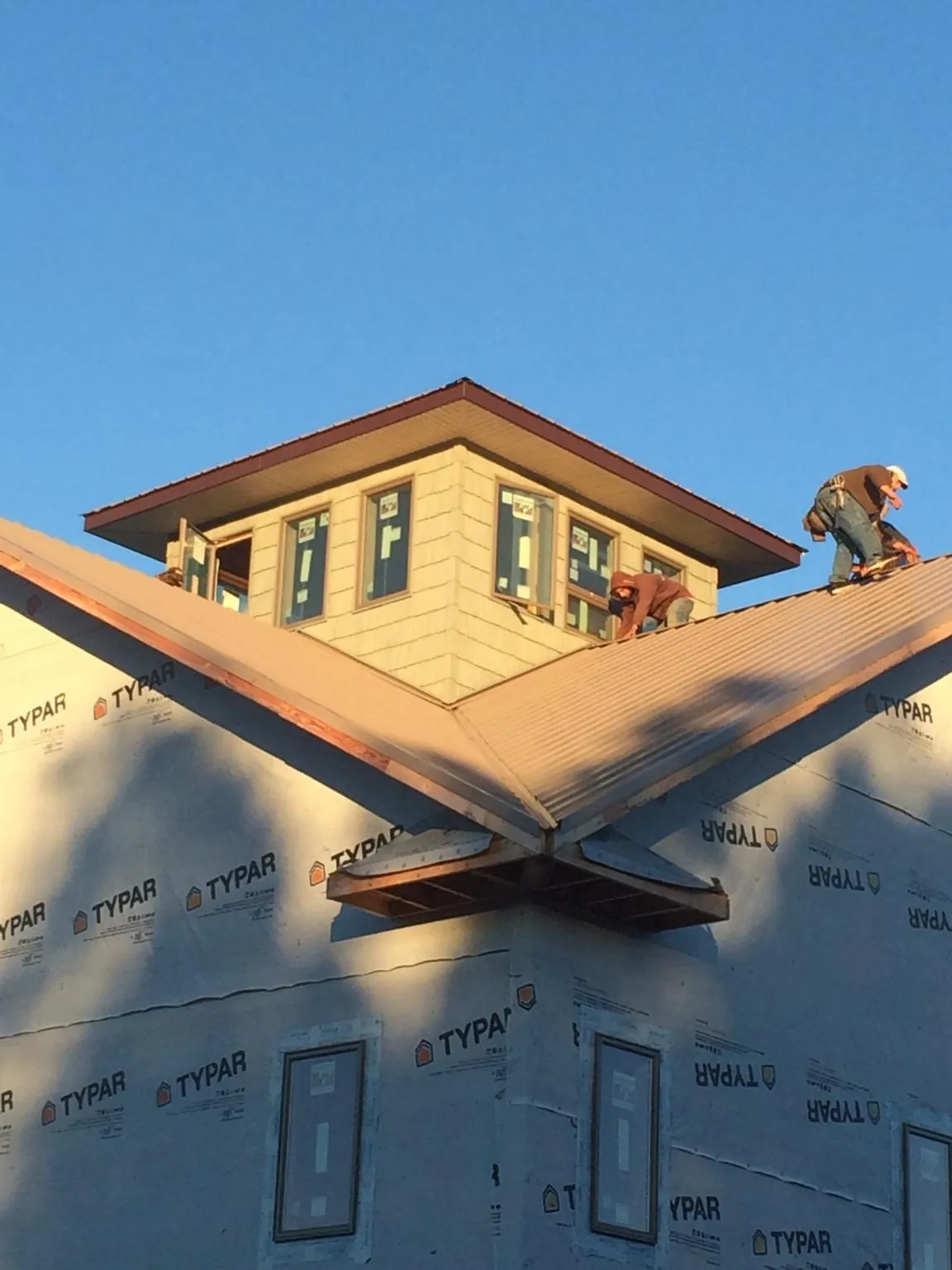 Roofers working around a rooftop cupola on a new metal roof at sunset — Roof Waterproofing in Mountain Ranch by Roofing Brothers